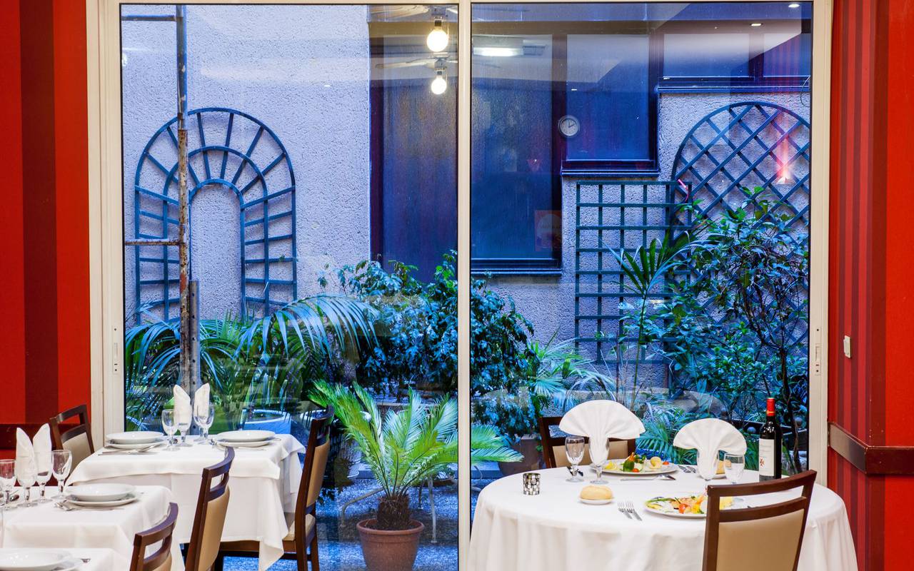 Repas au restaurant avec vue sur une grande baie vitrée donnant sur une petite terrasse, hotel lourdes proche sanctuaire, Hôtel Saint-Sauveur.