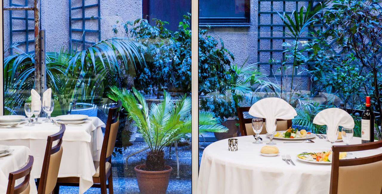 Table du restaurant avec vue sur notre espace de vie arboré et fleuri en extérieur, restaurant lourdes, Hôtel Saint-Sauveur.
